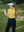 Model in yellow women's performance solid polo holding a golf club outdoors