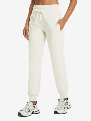 Model wearing women's stretch fleece lined water resistant joggers in beige, showcasing the front lower body view.