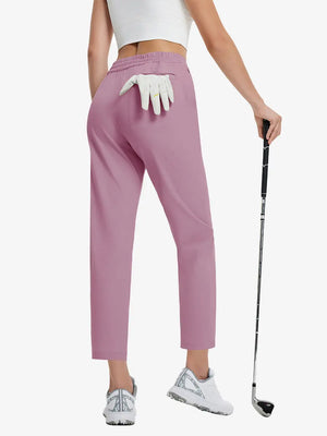 Back lower-body view holding a golf ball with glove in rear pocket wearing PINK Women's 7/8 Ankle Golf Track Pants.
