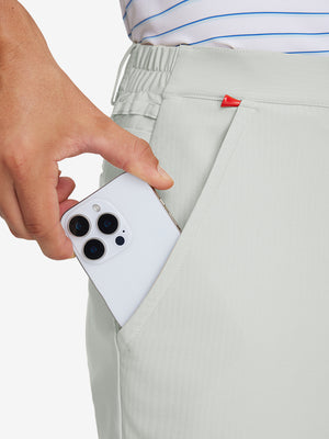 Hand placing an iPhone into pocket of lightweight flat front casual trousers in silver grey.