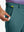 Hand placing a golf ball into pocket of water-resistant golf stretch nylon pants in dark teal.