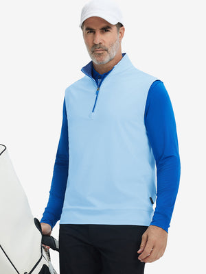 Model carrying golf bag, styled in light blue print collar quarter zip golf vest, relaxed sporty fit.