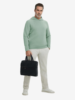 Model holding a bag, wearing beryl green texture solid hoodies pullover in full-body view.