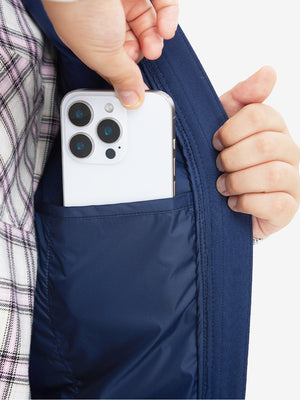 Close-up of boys full-zip fleece-lined puffer vest pocket holding a phone, practical detail in dark blue