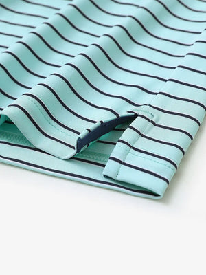 Hem slit detail of TURQUOISE/NAVY STRIPE Youth Performance Golf Polo highlighting stitching and finish.