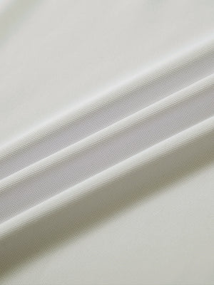 Close-up of cream ventilated pique performance polo fabric texture.