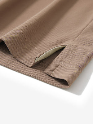 Close-up of the hem vent on the light brown ventilated pique performance polo, showing the side split for movement