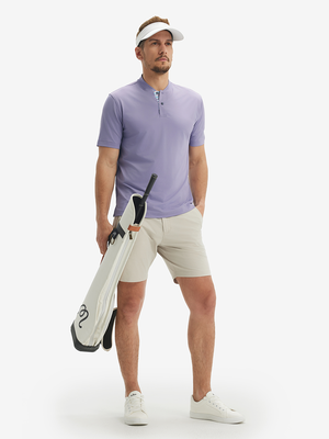 Full-body front view: model in lavender moisture-wicking short sleeve henley shirt holding golf bag.